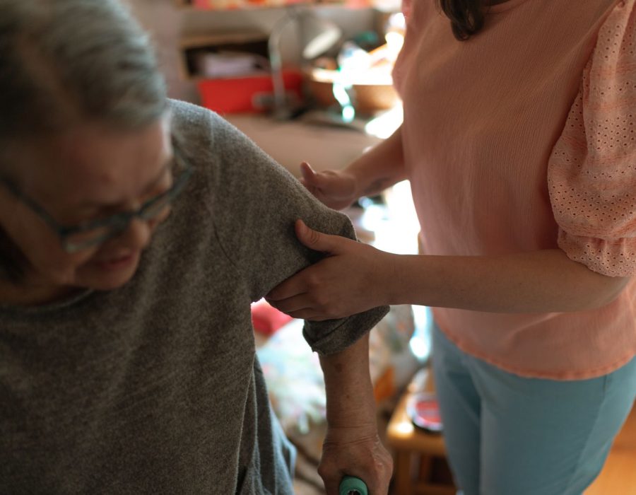 Pflegekraft stützt eine ältere Frau beim Gehen