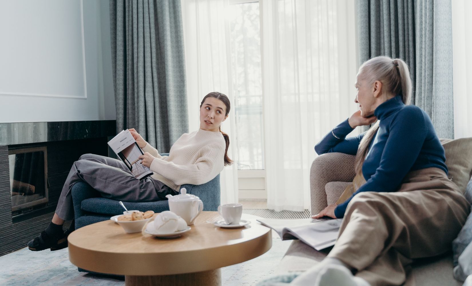 Pflegekraft und Seniorin im Gespräch im hellen Wohnzimmer