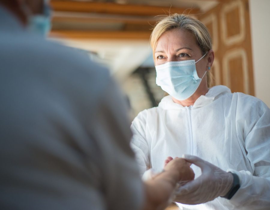 Pflegekraft mit Schutzkleidung bei der Behandlungspflege